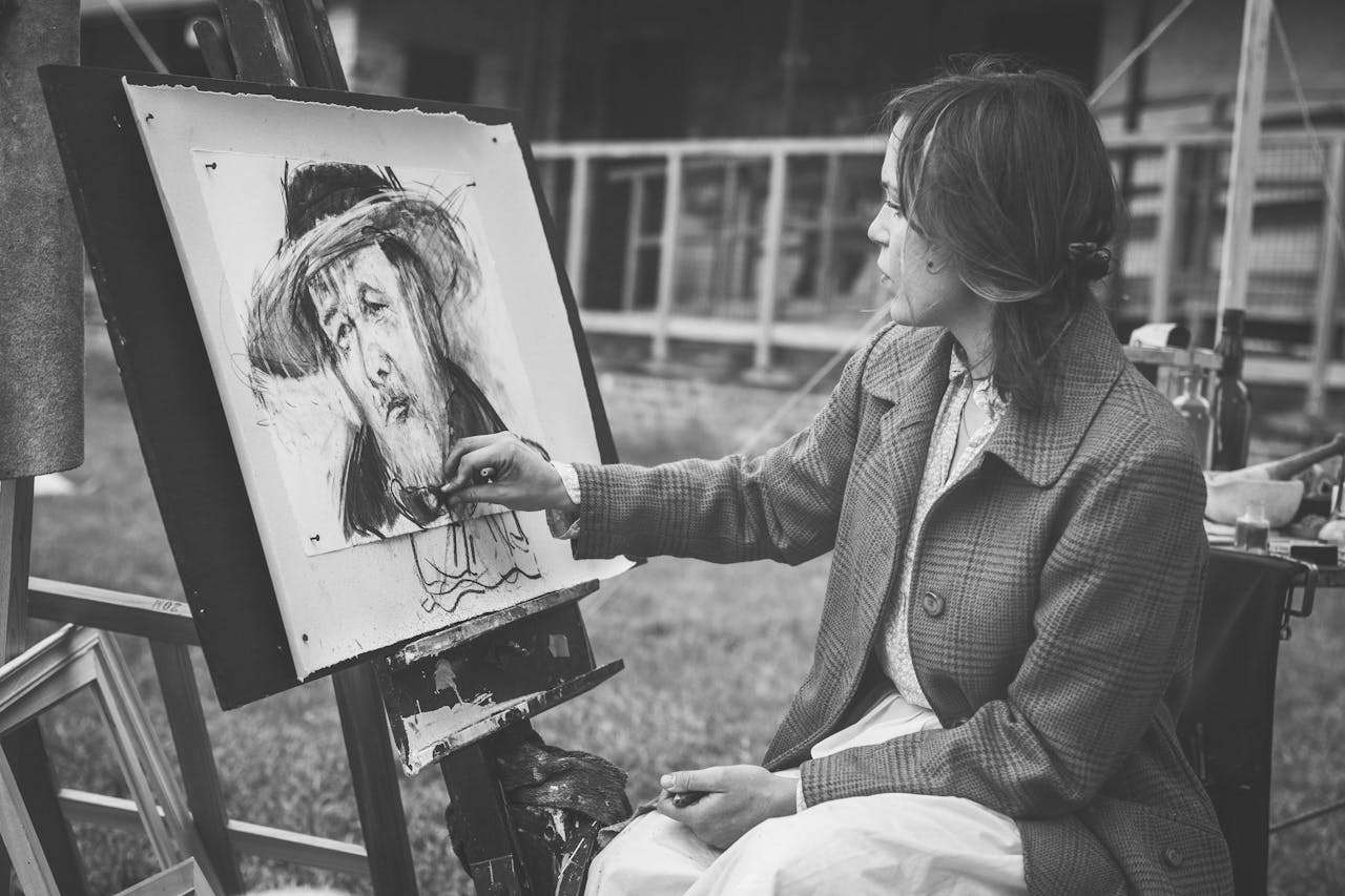 Woman painting a portrait outdoors in black and white.